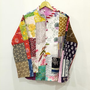 Può includere: Una giacca a maniche lunghe caratterizzata da un design patchwork realizzato con vari tessuti di cotone con diversi motivi floreali, geometrici e astratti in colori tra cui rosso, giallo, blu, bianco e nero. Presenta un colletto alla coreana e bottoni rosa.