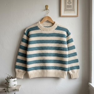 May include: A long-sleeve crochet sweater featuring horizontal stripes in alternating cream and teal colors. The garment has a ribbed crew neckline, ribbed cuffs, and a ribbed hem, constructed with a consistent textured stitch pattern throughout.