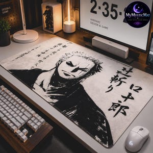 Op de afbeelding: Een rechthoekige bureaumat met een zwart-witte illustratie in inktstijl van een mannelijk anime-personage met kort haar en een strenge uitdrukking. Het ontwerp bevat verticaal en horizontaal gedrukte Japanse kalligrafiekarakters.