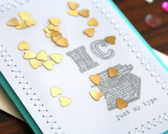 Tarjeta personalizada de feliz aniversario o de San Valentín: iniciales estampadas a mano "Just My Type" con diseño de corazones dorados y confeti.