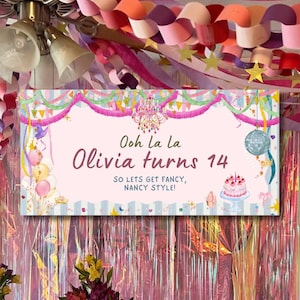 May include: A rectangular party banner with a light pink center and blue striped borders. It features a chandelier, a disco ball, a cake, and balloons. The text reads: Ooh La La, Olivia turns 14, SO LETS GET FANCY, NANCY STYLE! It is decorated with pink fringe.