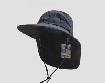 Könnte beinhalten: Marineblauer Sonnenhut mit breiter Krempe und Nackenschutz. Der Hut hat ein kleines Logo und ein Etikett mit Text und UV-Schutzangabe. Er ist für Outdoor-Aktivitäten konzipiert und bietet Sonnenschutz.