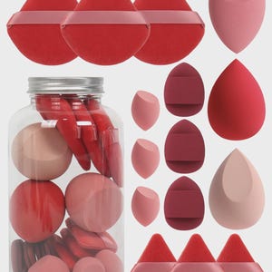 May include: A clear plastic jar filled with various red and pink makeup sponges and powder puffs. Beside the jar are additional makeup sponges in teardrop and wedge shapes, along with several red triangular powder puffs with ribbon straps.