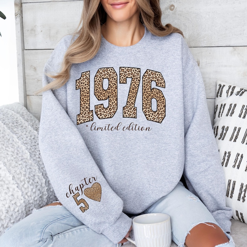 May include: A light gray crewneck sweatshirt featuring the number 1976 in a brown and black leopard print pattern, with the text "limited edition" below it. The sleeve displays the text "chapter 50" next to a leopard print heart icon.
