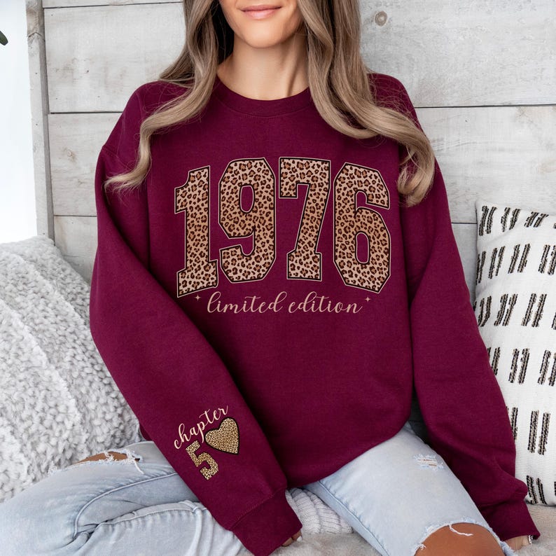 May include: A maroon crewneck sweatshirt featuring the year 1976 in a large leopard print font across the chest, with the text "limited edition" below it. The left sleeve displays the text "chapter 5" above a small leopard print heart and the number 5.
