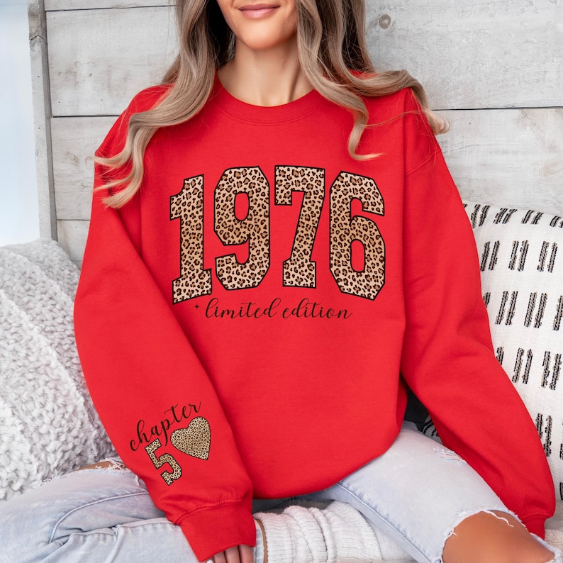 May include: A bright red crewneck sweatshirt featuring the year 1976 in a large leopard print font across the chest, with the text "limited edition" below it. The left sleeve displays the text "chapter 50" accompanied by a leopard print heart.