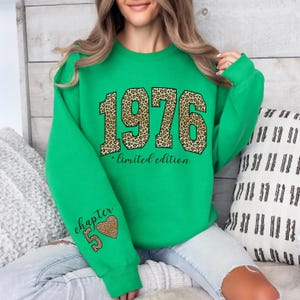 May include: A bright green long-sleeve sweatshirt featuring the year 1976 in a large leopard print pattern across the chest, with the text limited edition below it. The left sleeve displays the text chapter 50 and a leopard print heart graphic.