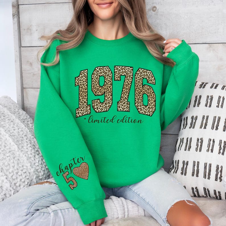 May include: A bright green long-sleeve sweatshirt featuring the year 1976 in a large leopard print pattern across the chest, with the text limited edition below it. The left sleeve displays the text chapter 50 and a leopard print heart graphic.