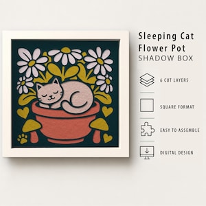 May include: A square shadow box featuring a layered paper design of a sleeping cat inside a terracotta-colored flower pot, surrounded by white daisies, yellow hearts, and mushrooms on a dark background. Text reads Sleeping Cat Flower Pot SHADOW BOX.