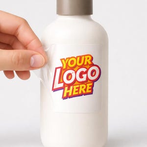 May include: A white opaque bottle with a brown cap featuring a clear rectangular sticker being applied to the surface. The sticker displays the text YOUR LOGO HERE in bold red and yellow letters with a purple outline on a transparent background.