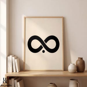 Pode incluir: Uma impressão de arte de parede emoldurada apresentando um símbolo de infinito preto em negrito centralizado em um fundo cor de creme. Abaixo do centro do laço do infinito, há um pequeno ponto preto. A obra está em uma moldura de madeira clara.