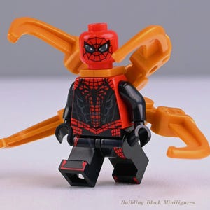 Peut inclure: Une figurine en plastique rouge et noire de type bloc de construction avec un motif d'araignée sur le torse et la tête. Elle possède quatre bras mécaniques orange dans le dos et porte le texte Building Block Minifigures en bas.