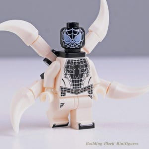 Peut inclure: Une figurine de bloc de construction en plastique avec une tête noire ornée d'un motif de toile d'araignée blanche et des yeux bleu clair. Le torse est blanc avec un emblème d'araignée noir. Quatre appendices blancs courbés sont fixés au dos.