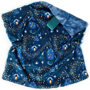 May include: A dark blue baby blanket with a firefly and jar pattern. The blanket has a soft, plush texture with a blue faux fur trim. A green ribbon is attached to the blanket.