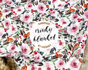 May include: A handmade minky blanket with a floral pattern. The blanket features a white background with pink roses, red berries, and green and brown leaves. The text "handmade minky blanket by iviebaby" is in a circular design.