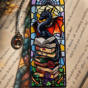 Puede incluir: Un marcapáginas rectangular de metal con una ilustración estilo vidriera que muestra un dragón azul oscuro sobre una pila de libros. El diseño incluye rosas rojas y moradas, enredaderas verdes y un pequeño dije circular unido por una cadena.