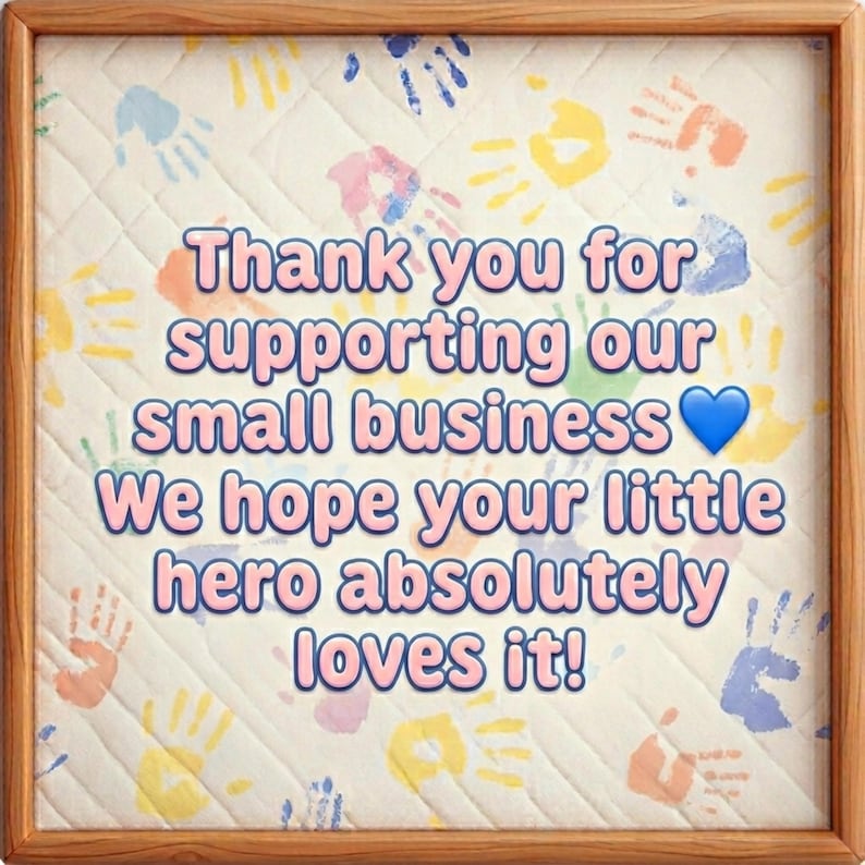 May include: A framed print with a quilted background featuring colorful handprints. The text reads "Thank you for supporting our small business" followed by "We hope your little hero absolutely loves it!"
