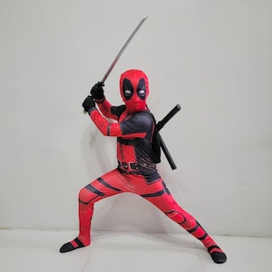 May include: A full-body red and black spandex costume featuring a mask with white eye patches. The suit includes a printed utility belt design and is worn with a black harness holding two black-handled swords, one held overhead.