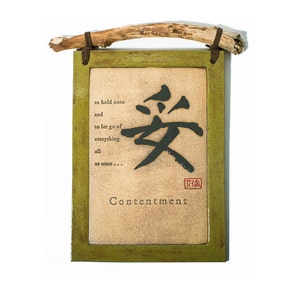 May include: A framed wood sign with a green frame and a beige background. The sign features a black Chinese character with the word "Contentment" written below it. The text "to hold onto and to let go of everything all at once..." is written above the character.