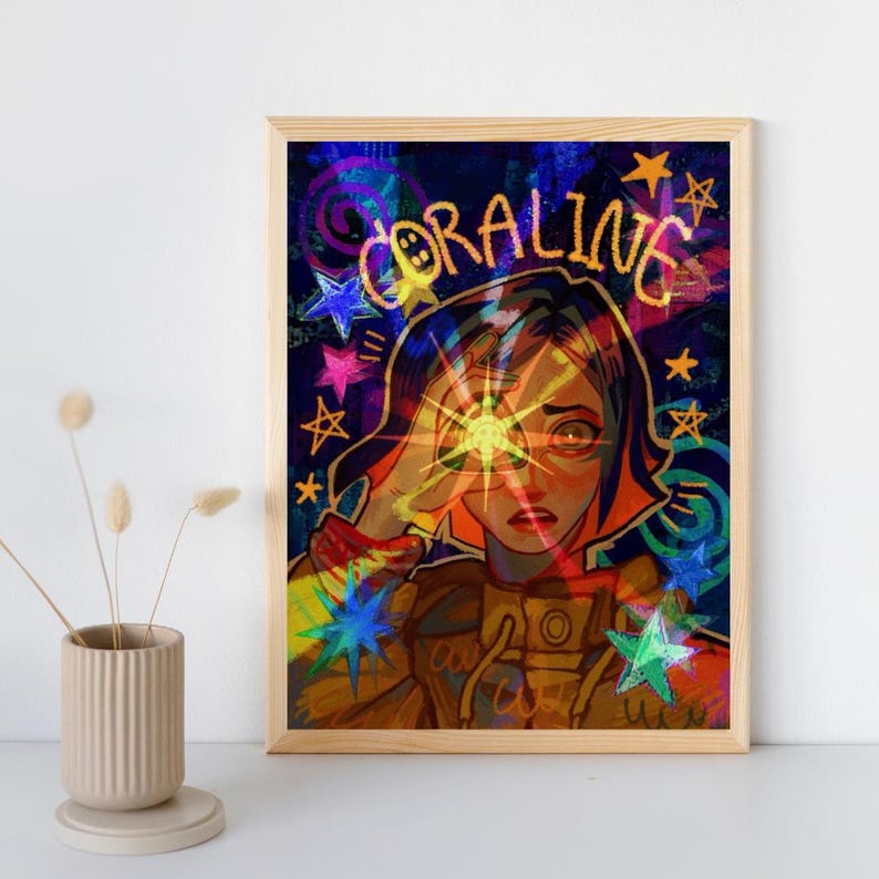 May include: A framed digital art print featuring a stylized illustration of a character with dark hair and a yellow jacket. The word CORALINE is written in yellow above the character, surrounded by colorful stars and swirls on a dark background.