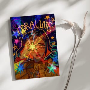 May include: A rectangular art print featuring a stylized illustration of a character with short hair wearing a yellow jacket. The text CORALINE is written in yellow at the top. The background is dark blue with colorful stars and swirling patterns.
