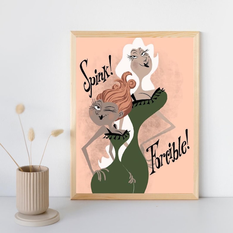 May include: A framed art print featuring two stylized female figures in green dresses against a peach background. The figure on the left has reddish-brown hair and the text Spink! above, while the figure on the right has white hair and the text Forcible! below.