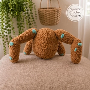May include: A brown crocheted plush toy with long limbs and small light blue circular accents. The item is labelled with text that reads Digital PDF Crochet Pattern. The plush has a textured, yarn-based surface and a rounded central body shape.