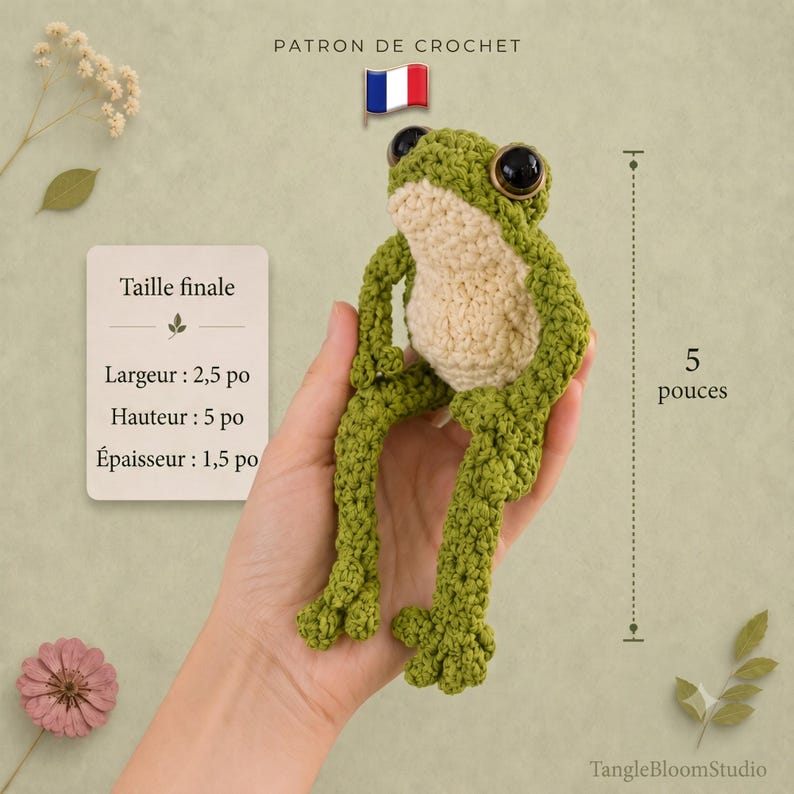 May include: A green and cream crocheted frog with large black eyes. A text card displays dimensions: width 2.5 inches, height 5 inches, thickness 1.5 inches. A vertical measurement line indicates a height of 5 inches. The text reads PATRON DE CROCHET.
