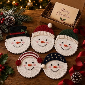May include: Five round, cream-colored crochet snowman coasters, each featuring a unique winter hat or earmuffs, black eyes, a stitched smile, and an orange nose. One coaster wears a black top hat, another a red beanie, a green beanie, red earmuffs, or a navy blue hat with gold stars.