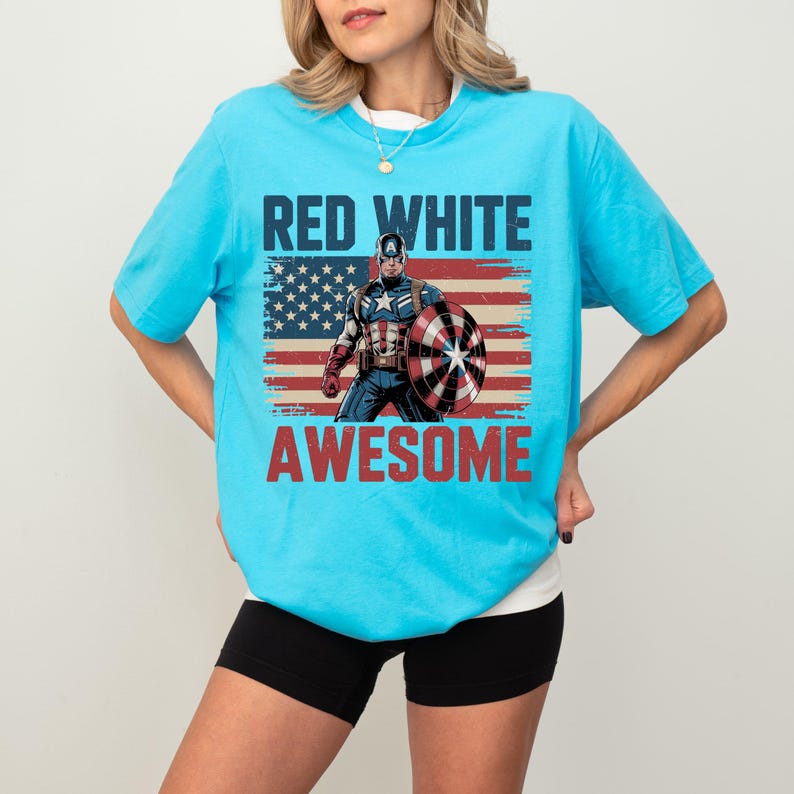 May include: A bright blue short-sleeve t-shirt featuring a graphic of Captain America holding a shield in front of a distressed American flag. The text RED WHITE and AWESOME is printed in bold blue and red letters above and below the graphic.