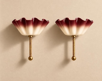 May include: Two wall sconces featuring ruffled, bowl-shaped shades with a gradient colour transition from deep burgundy at the top to cream at the base. Each shade is supported by a straight, metallic brass-toned rod ending in a spherical finial.