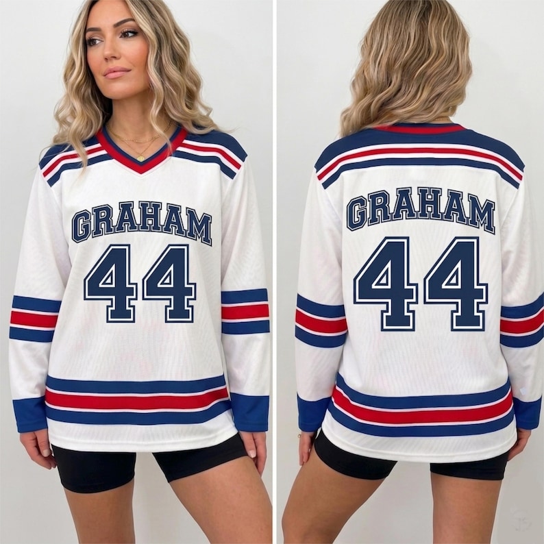 May include: A white long-sleeve jersey featuring a V-neck collar, blue and red horizontal stripes on the sleeves and hem, and the name GRAHAM with the number 44 printed in blue on both the front and back of the garment.