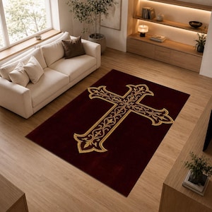 May include: A rectangular area rug featuring a deep burgundy background with a large, centred gold cross motif. The cross is decorated with intricate, symmetrical filigree patterns in a lighter gold tone, creating a bold contrast against the dark fabric.