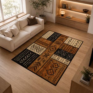 May include: A rectangular area rug with a geometric pattern in shades of black, brown, and beige. The rug features various shapes and designs, including arrows, zigzags, and diamond shapes. The rug is placed on a hardwood floor in a living room setting.