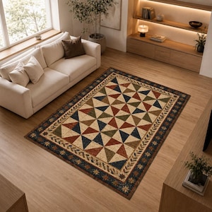 Könnte beinhalten: Ein rechteckiger Teppich mit einem geometrischen, von Patchwork inspirierten Muster aus Dreiecken in Marineblau, Olivgrün und Rostrot auf cremefarbenem Grund, umrahmt von einer dunklen Bordüre mit Blatt- und Sternmotiven.