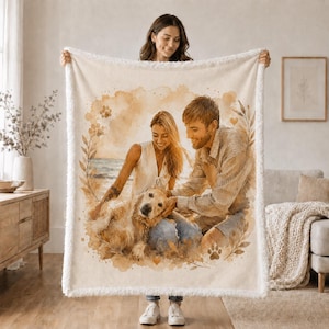 K&ouml;nnte beinhalten: Eine cremefarbene Wohndecke mit einer Illustration im Aquarellstil, die eine Person und einen Hund am Strand zeigt. Das Motiv ist von botanischen Elementen und Pfotenabdr&uuml;cken umrahmt und hat einen weissen Rand aus Sherpa-Fleece.