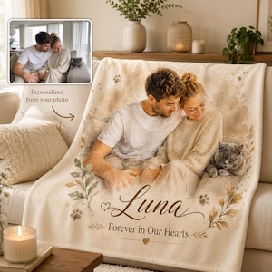 K&ouml;nnte beinhalten: Eine cremefarbene Fleecedecke mit einem aufgedruckten Foto einer Person und einer Katze. Das Design enth&auml;lt botanische Illustrationen, Pfotenabdr&uuml;cke und den Text "Luna" gefolgt von dem Schriftzug "Forever in Our Hearts" in Schreibschrift.