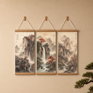 May include: A set of three vertical wall hangings featuring landscape paintings of mountains, waterfalls, and trees with red foliage. Each print is mounted on light wood frames with white hanging cords and includes black Chinese calligraphy text.
