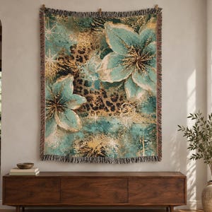 May include: A woven throw blanket featuring a vibrant teal and gold floral pattern layered over a brown and black leopard print background. The rectangular textile has a fringed edge and displays large, stylized blossoms with starburst accents.