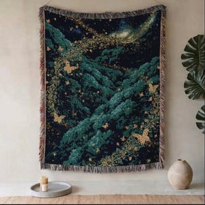 Puede incluir: Un tapiz de pared tejido rectangular con un fondo azul marino oscuro, follaje de bosque verde intenso y mariposas doradas. El diseño incluye intrincados patrones de enredaderas doradas y bordes con flecos en todos los lados.