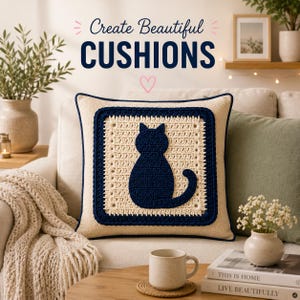 Puede incluir: Un cojín cuadrado con un panel central de ganchillo color crema y una silueta de gato de ganchillo azul marino oscuro en el centro. El cojín está bordeado por un marco de ganchillo azul marino oscuro y tiene el texto Create Beautiful CUSHIONS.
