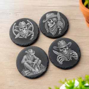 May include: A set of four round black slate coasters, each featuring a detailed grey engraved illustration of a skeleton wearing a cowboy hat. The designs depict various scenes including a skull with a knife and rope, and a seated skeleton.