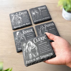 May include: Five square black slate coasters featuring white engraved illustrations and text for fantasy character classes: Druid, Wizard, Ranger, Fighter, and Cleric. Each coaster lists specific abilities and a thematic motto, such as Faith Is My Strength.