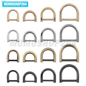 May include: A collection of sixteen metal D-rings arranged in a four-by-four grid, featuring four distinct metallic finishes including gold, silver, bronze, and gunmetal, with each row displaying four varying sizes of hardware.