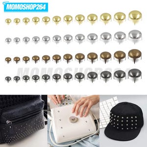 May include: A collection of metal upholstery tacks in four finishes: gold, silver, bronze, and gunmetal, arranged in rows by size. Below, a black leather backpack, a white handbag, and a black baseball cap are decorated with these metal studs.