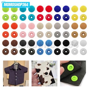 May include: A collection of round plastic snap buttons in various colors including green, blue, red, yellow, pink, beige, gray, brown, black, and white. The image also shows a dark blue shirt, a cow-print fabric item, and green snaps on fabric.