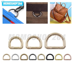 May include: A collection of metal D-rings with integrated spring-loaded gate clips, displayed in various sizes and metallic finishes including gold, silver, bronze, black, and rose gold, suitable for attaching straps to bags and backpacks.