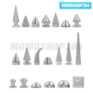 Op de afbeelding: Een verzameling zilverkleurige metalen studs en spikes in diverse vormen, waaronder kegelvormige, gebogen, koepelvormige en vierkante ontwerpen. De items zijn in drie rijen gerangschikt tegen een witte achtergrond, met de tekst MOMOSHOP264 bovenaan.
