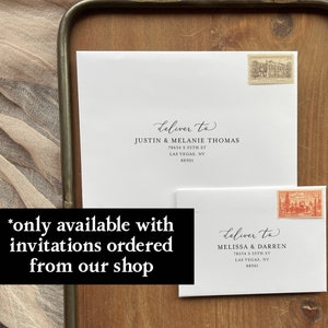 May include: Two white envelopes with black calligraphy and a handwritten address. The envelopes are on a wooden tray with a decorative shell and wax seals. The text on the envelopes reads "deliver to" followed by the name and address of the recipient. The text "*only available with invitations ordered from our shop" is written in black on a white background.