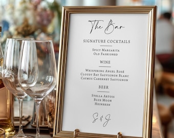 May include: A gold framed sign with the words "The Bar" in elegant script. The sign lists signature cocktails, wines, and beers. Two wine glasses are in the foreground, and the background is blurred.